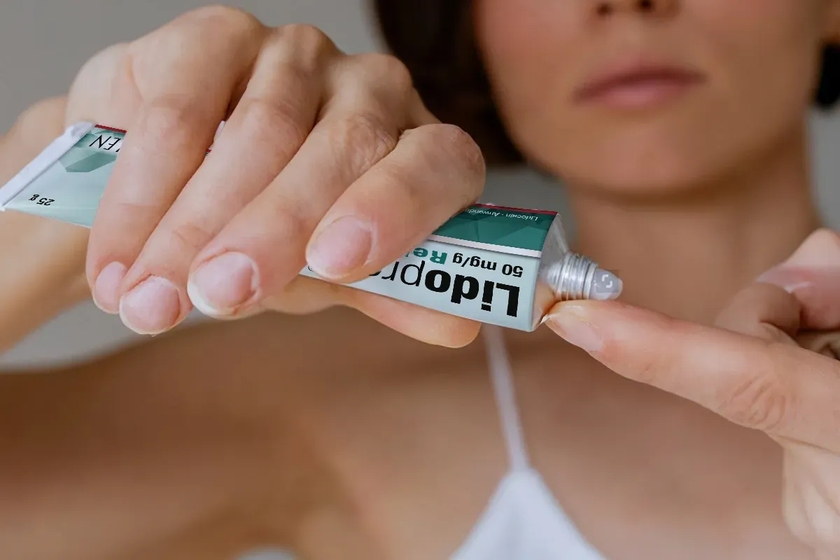 Easy Anwendung - immer dabei Eine weibliche Person drückt Creme aus einer Tube Lidoproct auf ihren Zeigefinger