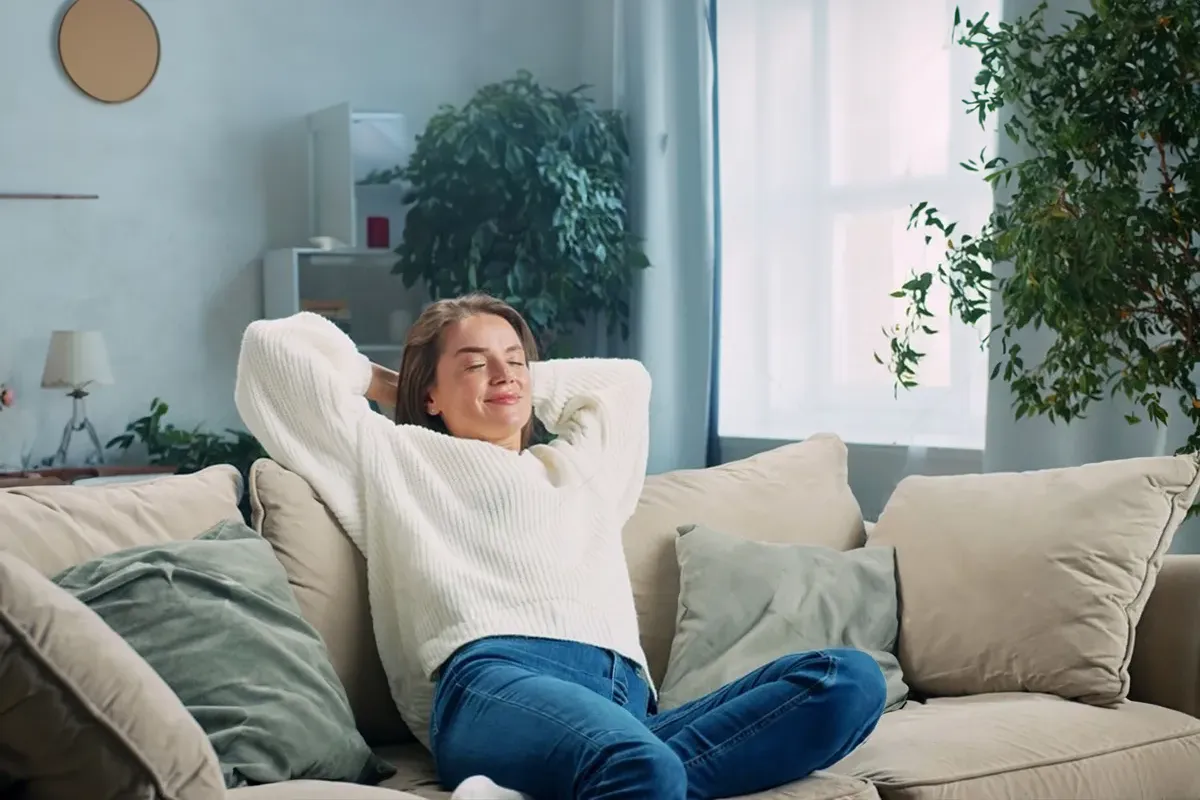 Rasche Linderung - direkt spürbar. Lidocain Eine weibliche Person liegt entspannt mit den armen hinterm Kopf verschränkt auf einer hellen Couch