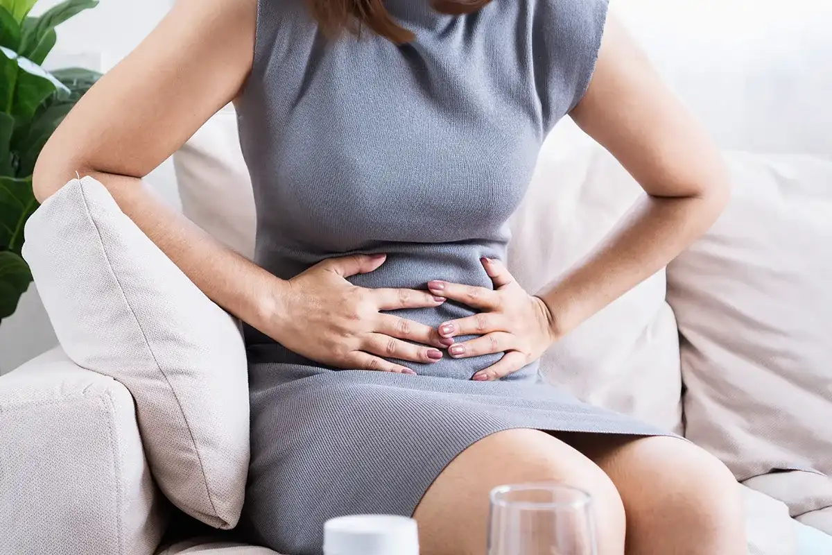 Analfissuren richtiges Verhalten Heilung fördern Eine weibliche Person, die sich mit beiden Händen den Bauchbereich hält