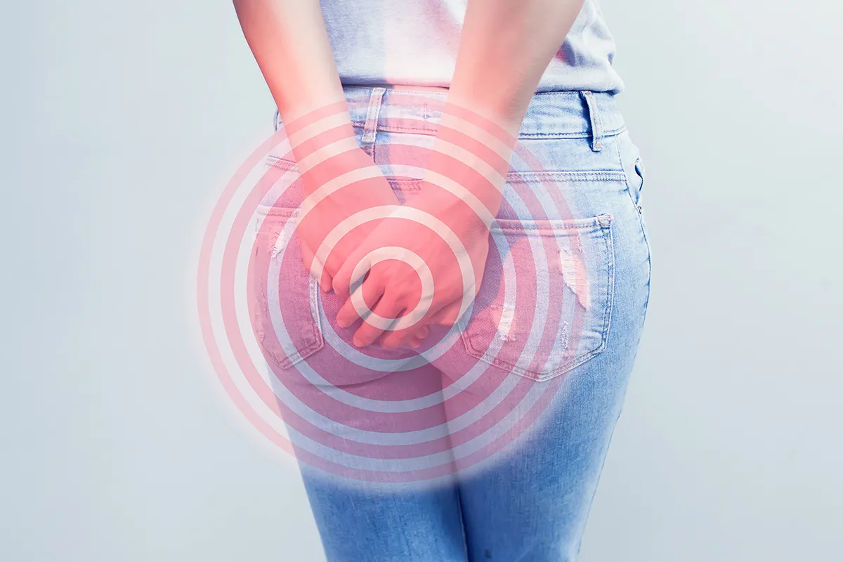 Eine Person hält sich beide Hände in der Höhe Ihrer Jeanshosentaschen auf das Gesäß. Schemenhaft sind rötliche Kreise über die gehaltene Stelle gemalt