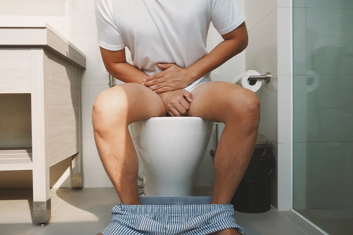 Salbe für den After Anwendung Hämorrhoiden Eine männliche Person nach vorne gebeugt auf einer Toilette