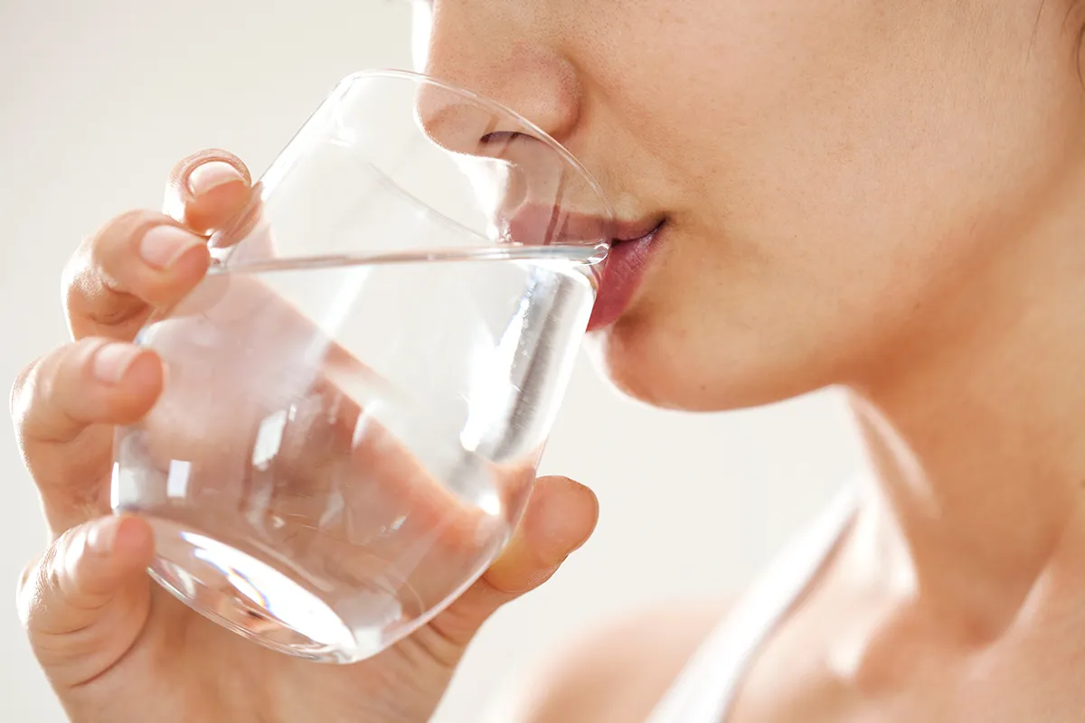 Ursachen bei Schmerzen beim Stuhlgang harter Stuhl Nahaufnahme eines Wasserglases, woraus eine weibliche Person trinkt