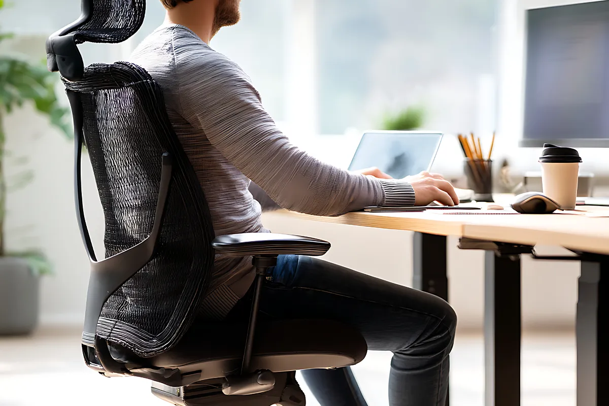 Ursachen Entzündungen im Analbereich Eine männliche Person an einem Schreibtisch sitzend mit einem kleinen und Großen Monitor darauf