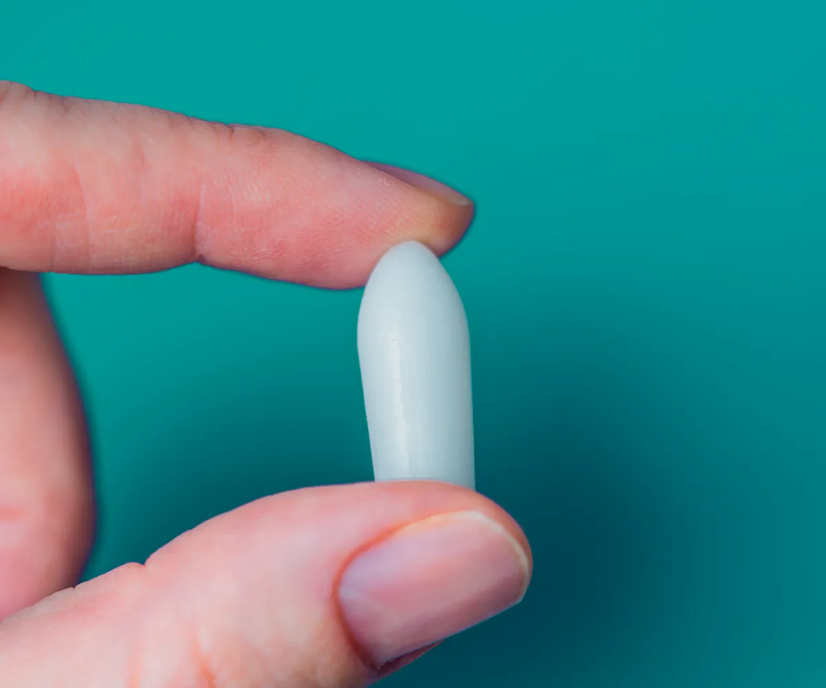 Vorteile von Zäpfchen Ein Zäpfchen zwischen Zeigefinger und Daumen